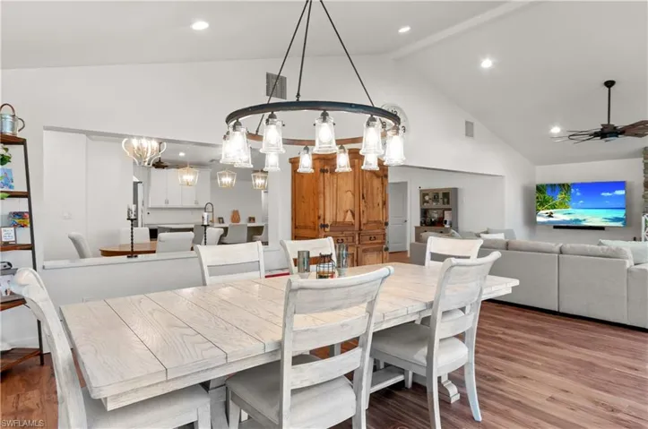 Dining space featuring wood finished floors, high vaulted ceiling, recessed lighting, a chandelier, and a ceiling fan