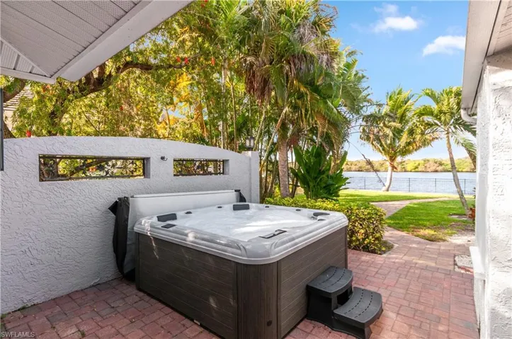 View of patio with a water view and a hot tub