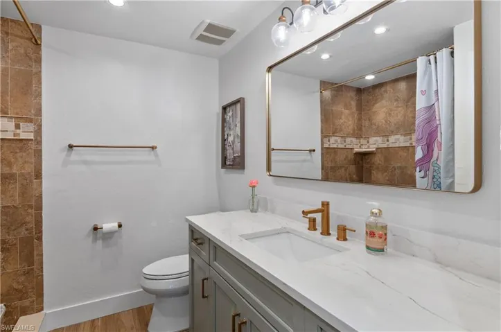 Bathroom featuring tiled shower, vanity, recessed lighting, and light wood-style floors