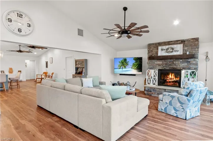 Living area with a ceiling fan, light wood-type flooring, a fireplace, recessed lighting, and high vaulted ceiling