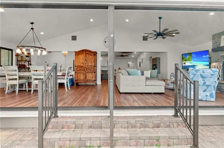 Living area with a large fireplace, recessed lighting, high vaulted ceiling, and a ceiling fan