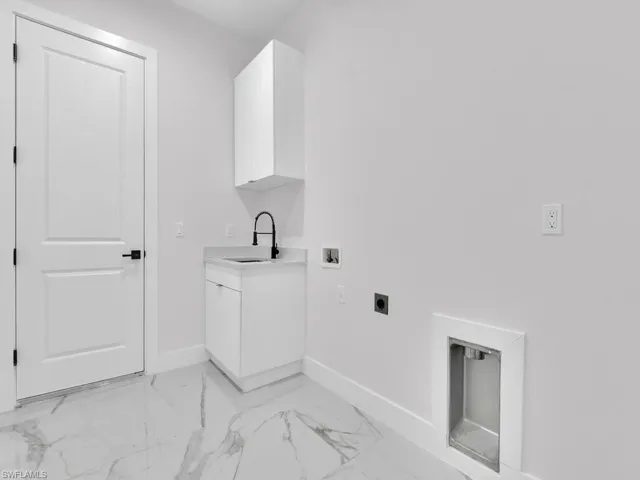Laundry area with electric dryer hookup, cabinets, sink, and hookup for a washing machine.