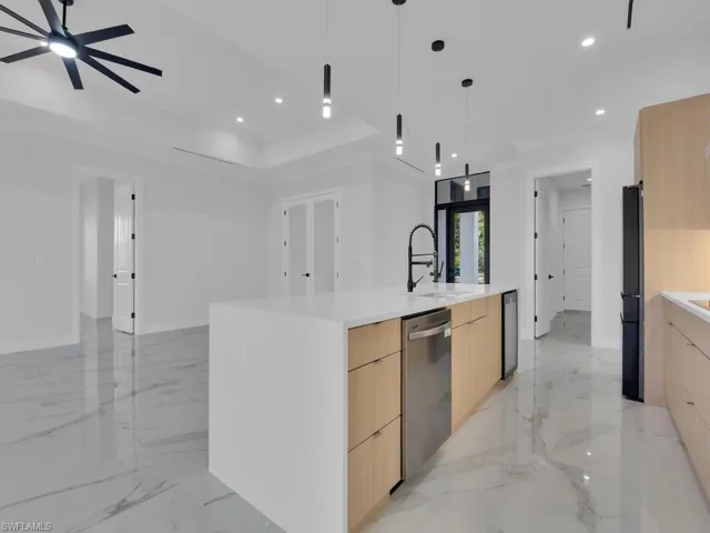 Kitchen featuring light brown cabinetry, stainless steel appliances, sink, a large island with sink, and pendant lighting