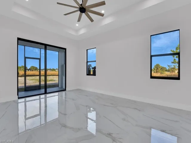 Unfurnished primary bedroom with a raised ceiling and ceiling fan