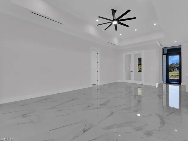 Unfurnished living room with a tray ceiling , ceiling fan and a Den.