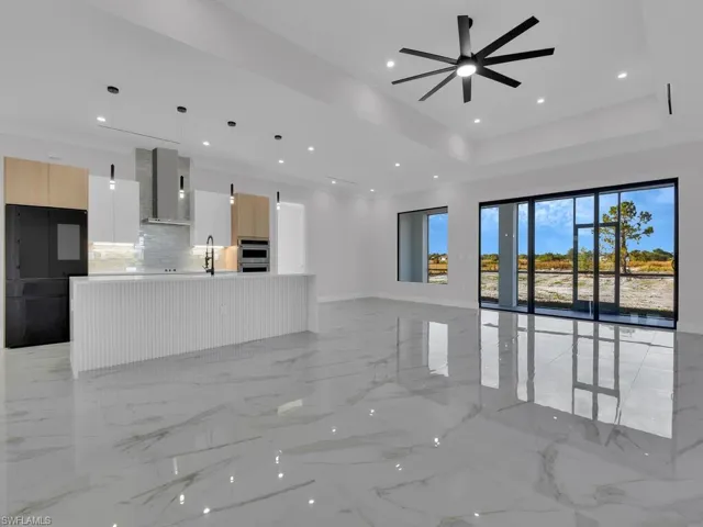 Unfurnished living room featuring a raised ceiling, ceiling fan, and sink. sliding door and an screened lanai.
