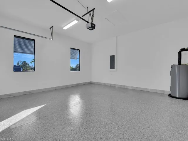 Garage featuring electric panel, a garage door opener, and water heater.
