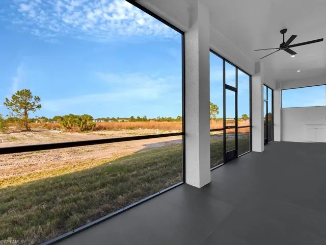 Unfurnished sunroom featuring ceiling fan, screened lanai and partial view of the backyard.