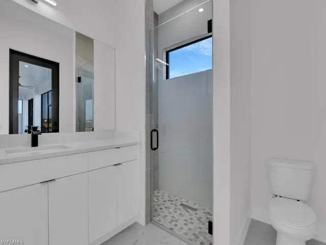 Bathroom with vanity, an enclosed shower, and toilet