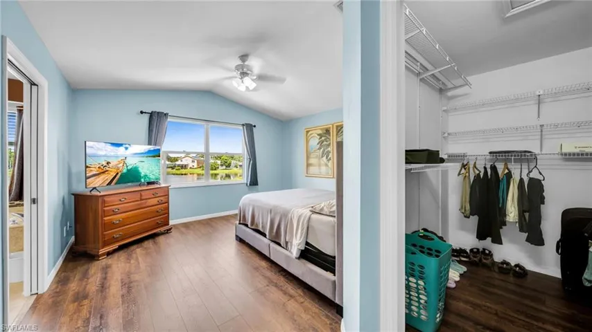 Master Bedroom featuring wood-style flooring, lofted ceiling, walk in Closet with Lake View