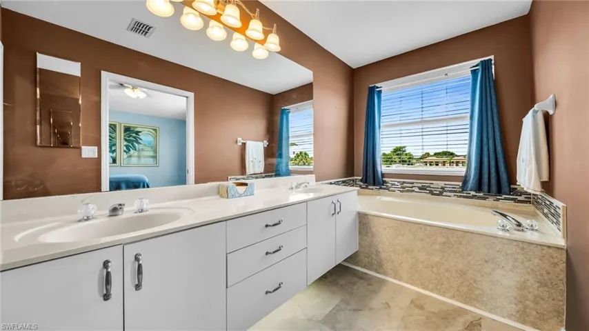 Ensuite bathroom featuring double vanity and a bath
