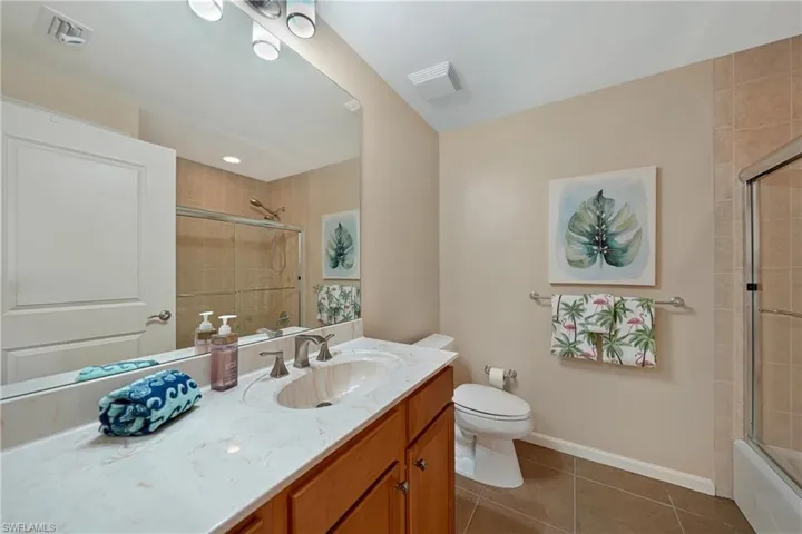 Bathroom with dark tile patterned flooring, vanity, and enclosed tub / shower combo