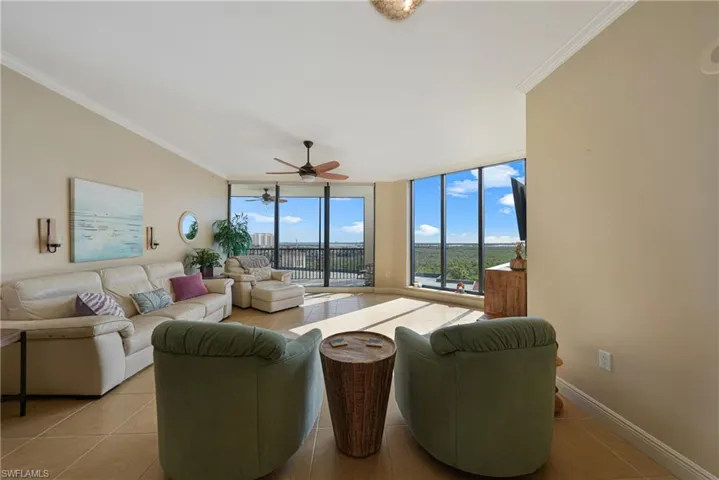 Living area featuring expansive windows, ornamental molding, light tile patterned floors, and a ceiling fan