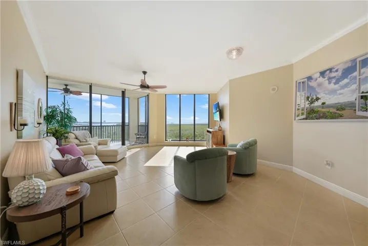Living room with a wall of windows, ornamental molding, and light tile patterned flooring