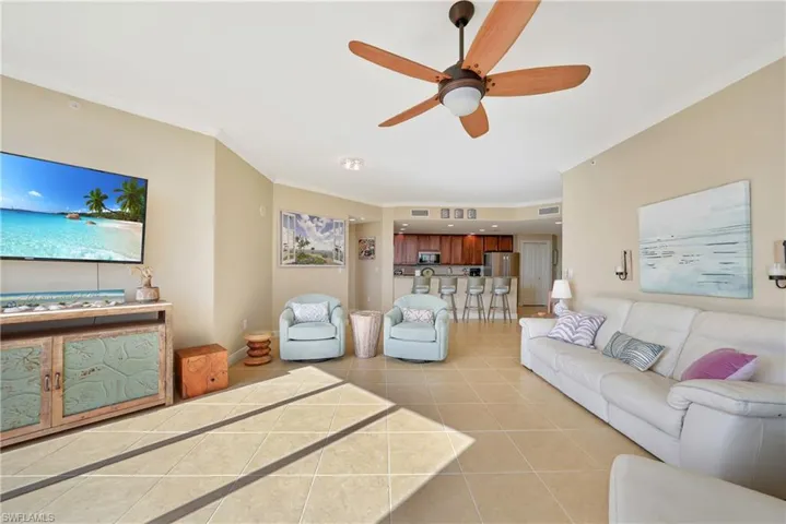 Living area featuring ornamental molding, light tile patterned floors, and a ceiling fan