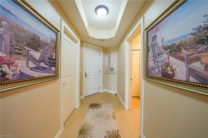 Corridor with a raised ceiling and light tile patterned flooring