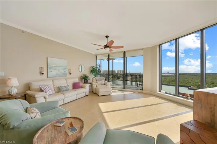 Tiled living room featuring floor to ceiling windows, ornamental molding, and a ceiling fan