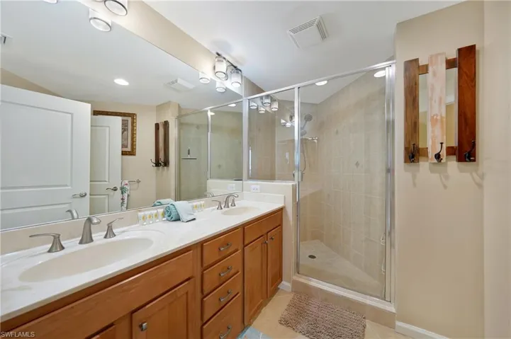 Bathroom with double vanity, a stall shower, light tile patterned floors, and recessed lighting