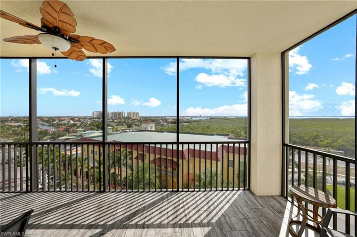 Unfurnished sunroom featuring plenty of natural light, a wall of windows, a view of city, a textured ceiling, and a textured wall