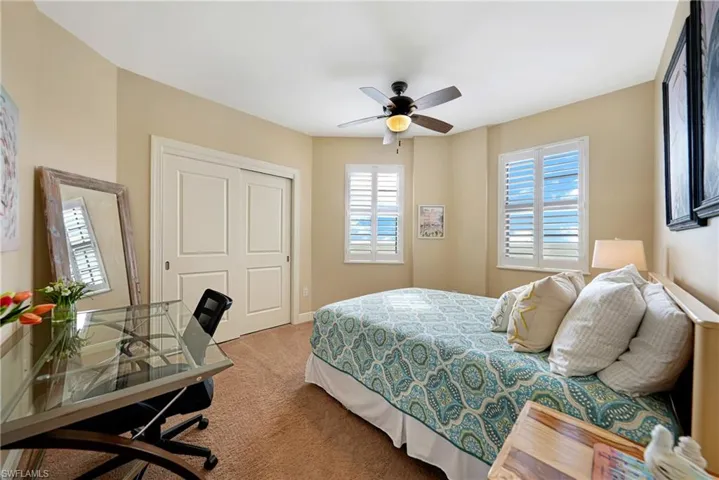Bedroom featuring carpet floors, a ceiling fan, a closet, and a desk
