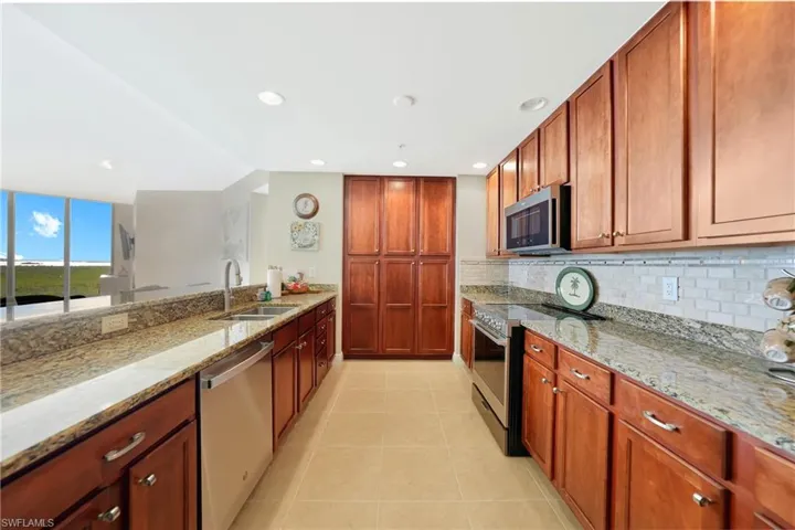 Kitchen with stainless steel appliances, light stone countertops, recessed lighting, brown cabinets, and light tile patterned floors