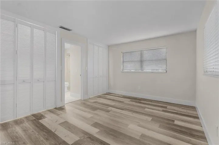 Unfurnished bedroom featuring ensuite bathroom and light hardwood / wood-style floors