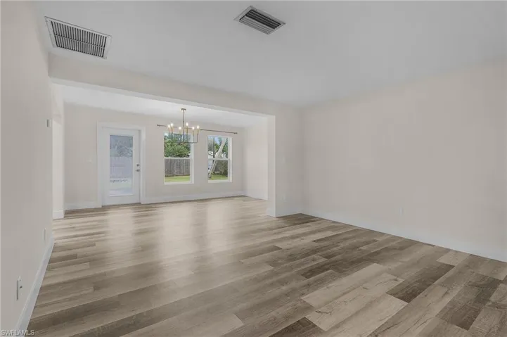 Unfurnished living room with a notable chandelier and light hardwood / wood-style floors