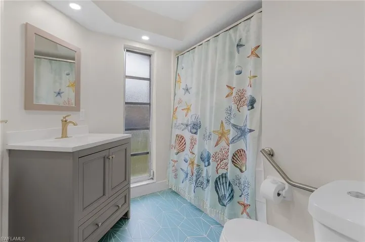 Bathroom with vanity, a shower with curtain, and toilet