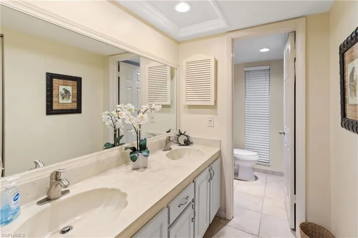 Bathroom with ornamental molding, vanity, toilet, and tile patterned floors