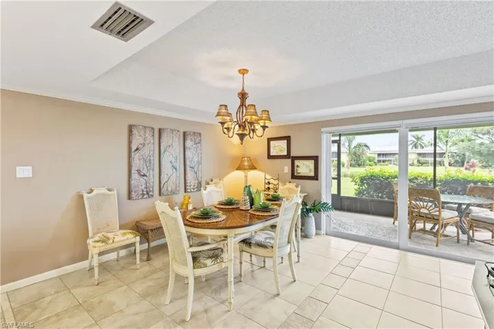 Dining room featuring light tile patterned floors, a textured ceiling, crown molding, and a chandelier