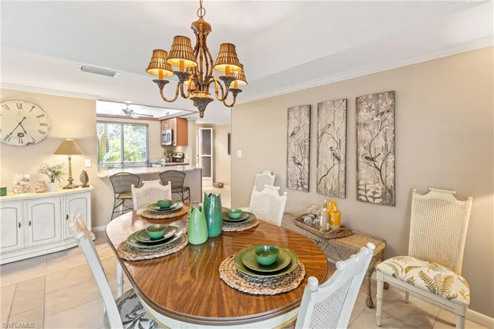Dining space featuring ornamental molding, light tile patterned floors, and a notable chandelier