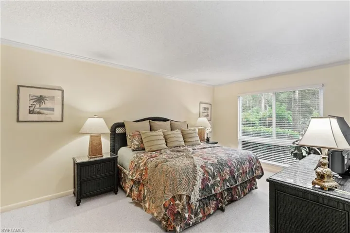 Bedroom with a textured ceiling, ornamental molding, and light carpet