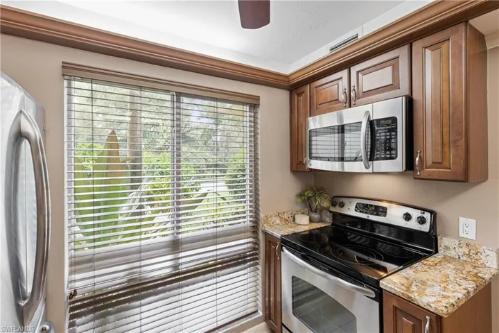 Kitchen with a textured ceiling, washer / dryer, stainless steel appliances, and light stone counters