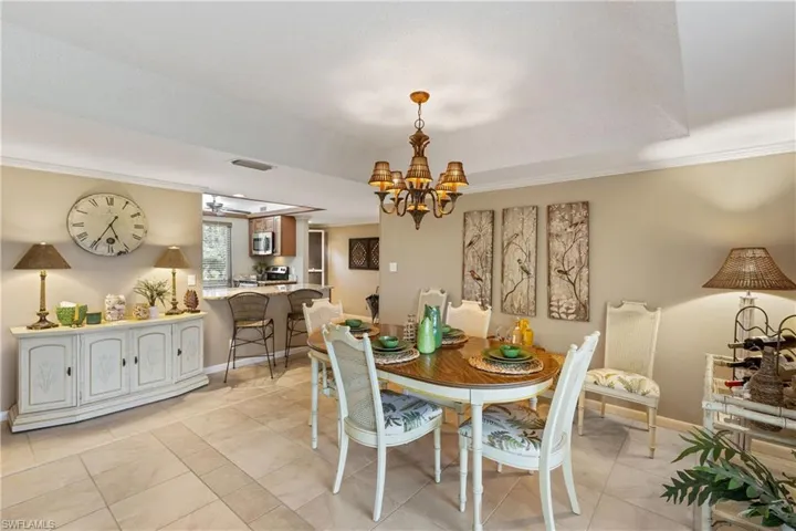 Dining area with light tile patterned floors, ornamental molding, and a chandelier