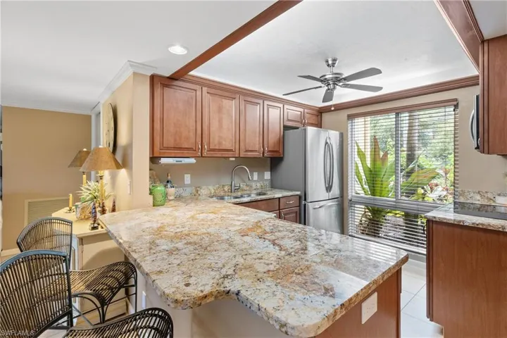 Kitchen with a breakfast bar, sink, kitchen peninsula, stainless steel appliances, and ceiling fan