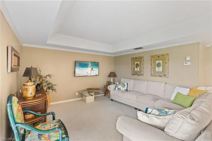 Carpeted living room with ornamental molding and a raised ceiling