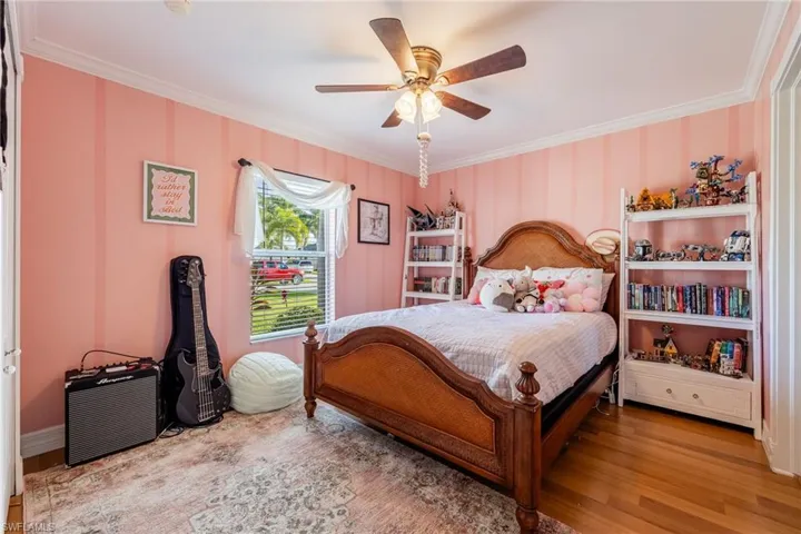Bedroom featuring ornamental molding, light wood-type flooring, and a ceiling fan