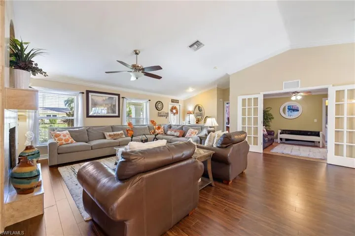 Living room with a ceiling fan, ornamental molding, lofted ceiling, french doors, and a high end fireplace