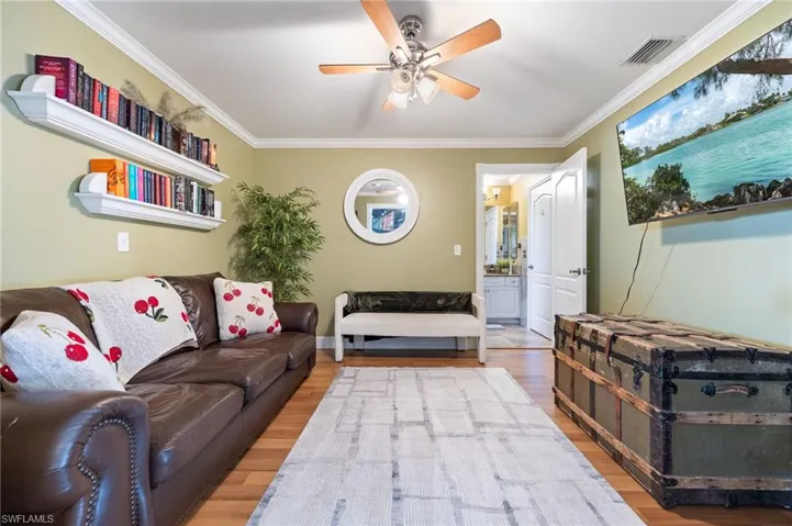 Living room featuring crown molding, wood finished floors, and a ceiling fan