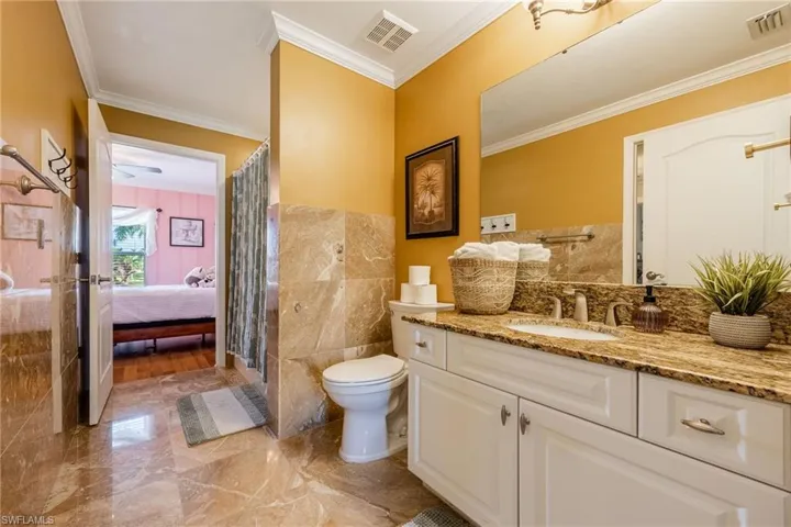 Bathroom featuring crown molding, vanity, tile walls, light marble finish flooring, and a shower stall
