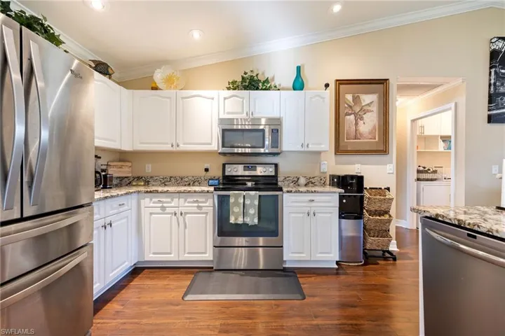 Kitchen featuring ornamental molding, appliances with stainless steel finishes, white cabinets, light stone counters, and recessed lighting