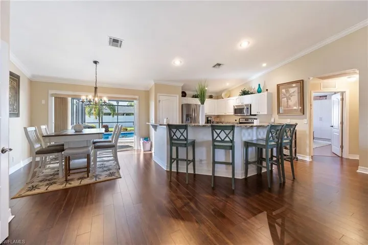 Kitchen with white cabinetry, a chandelier, stainless steel appliances, a breakfast bar, and recessed lighting