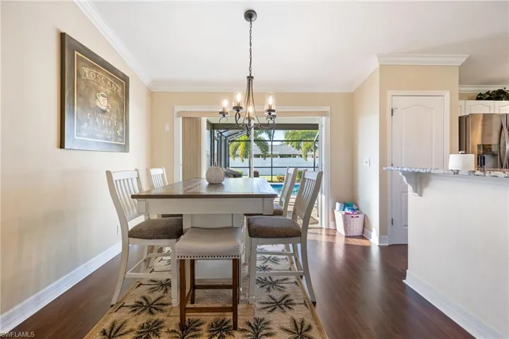 Dining room with dark wood-style floors, a chandelier, and crown molding