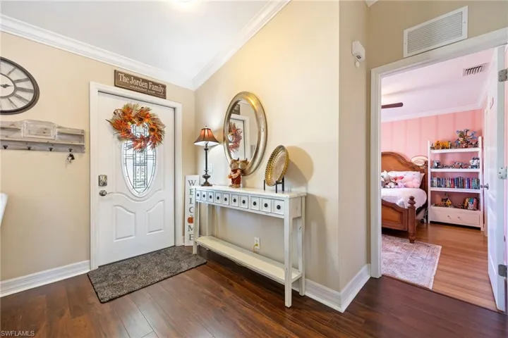 Entryway with ornamental molding and dark wood finished floors