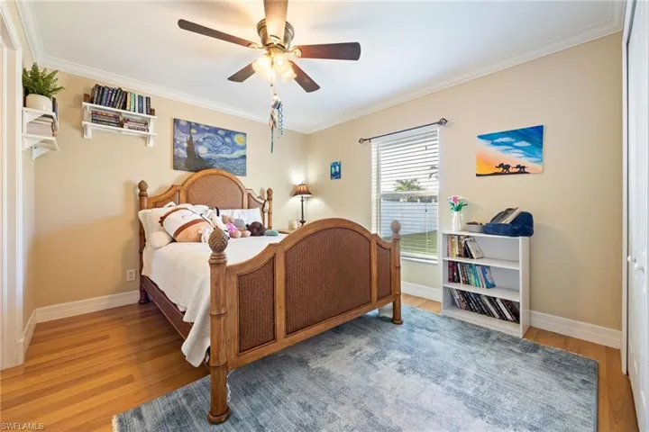Bedroom featuring ornamental molding, light wood finished floors, and a ceiling fan