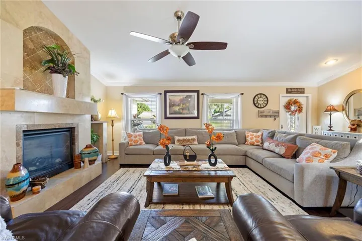 Living room with crown molding, wood finished floors, a tile fireplace, and ceiling fan
