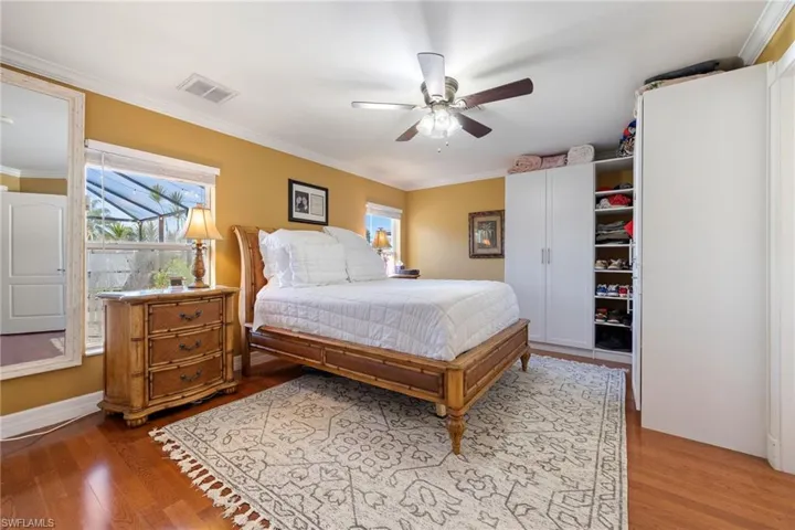 Bedroom with ornamental molding, multiple windows, light wood-style flooring, and ceiling fan