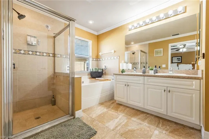 Bathroom with a bath, ensuite bath, a shower stall, double vanity, and recessed lighting