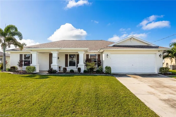 View of front of property with a porch, stucco siding, driveway, a front yard, and an attached garage