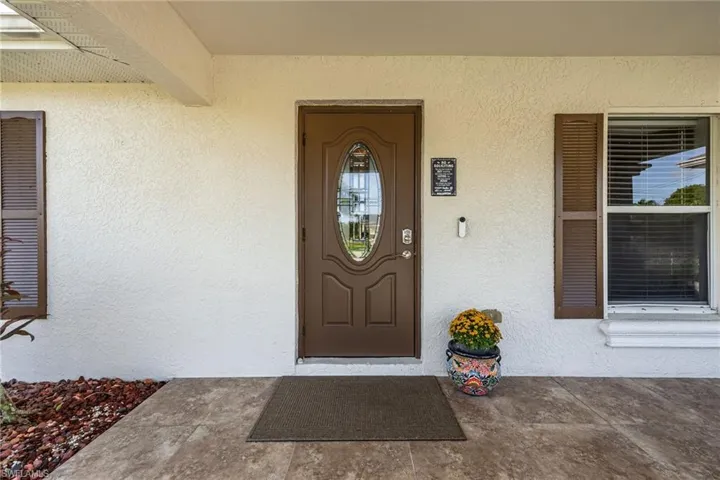 View of exterior entry featuring stucco siding and covered porch